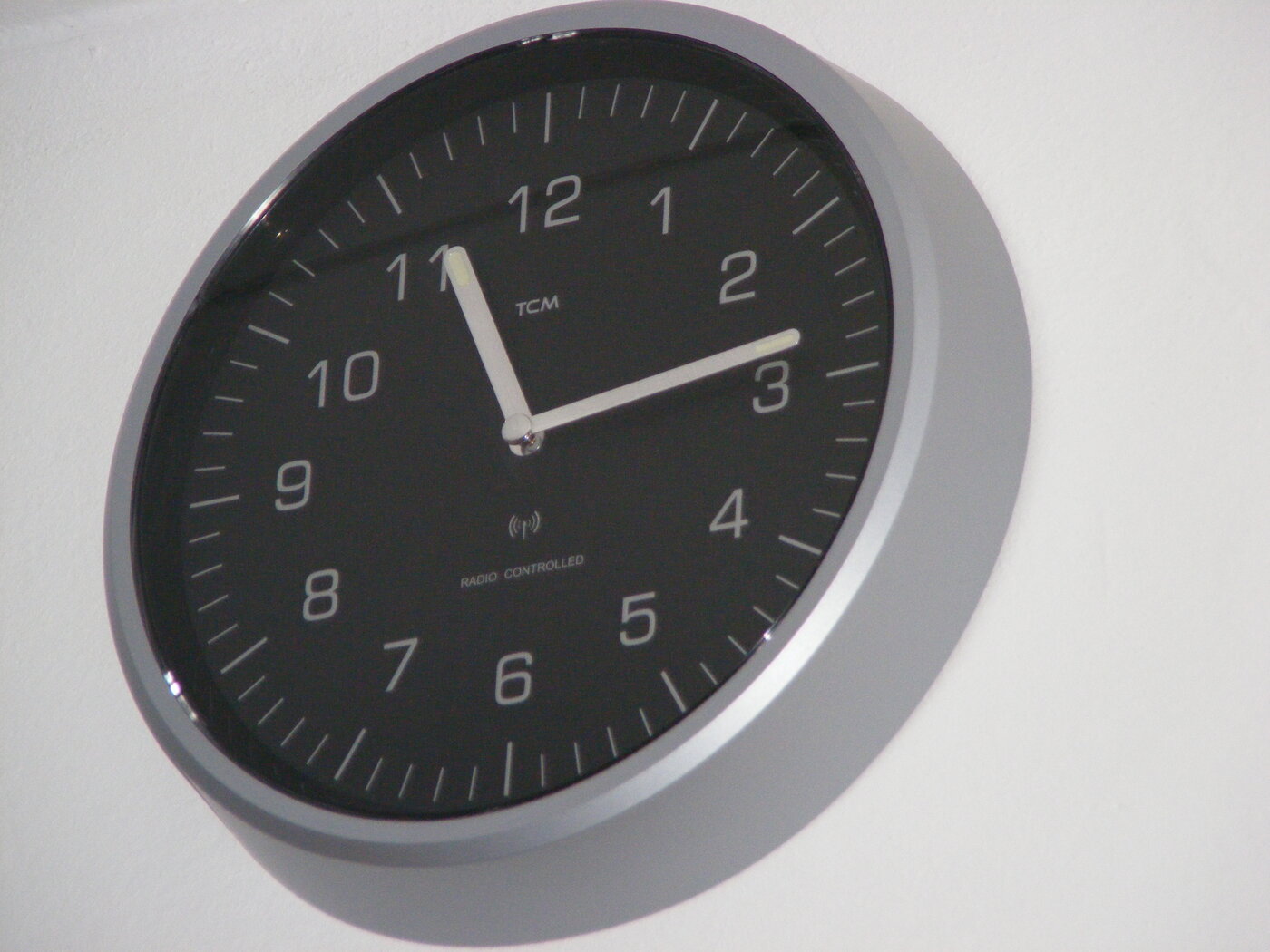 A photograph of a wall clock with hands, of the type that contains a radio receiver synchronized to a national time signal.